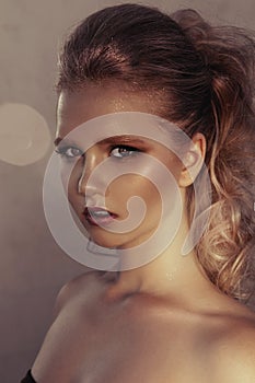 Glamour portrait of young fashion woman face with bright evening golden make up for party and tanned skin. Warm toning. Retouched