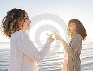 Glamour style photograph of two multiracial models, Caucasian and black Hispanic toasting with a glass of white wine by the