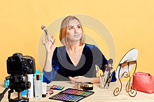 Glamourous female model posing for makeup advertisement holding brush