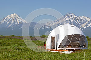 Glamping house in summer and volcano, rural landscape, tent houses in Kamchatka peninsula. Selective focus. photo