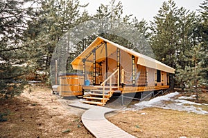 A glamping house with a swimming hot tub in a pine forest. photo