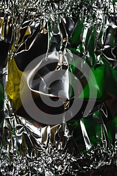 Glaring surface. Crumpled aluminum foil. Crinkled background. Colored sparkle. Selective focus