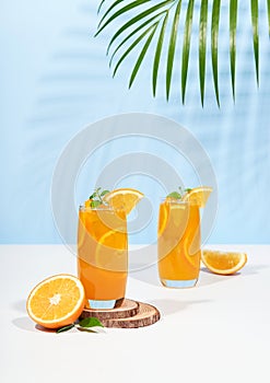 Glass of 100% Orange juice with orange slices fruits on pastel color background. Summer sea vacation and travel concept.