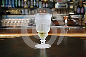 Glass with absinth on bar interior background. photo