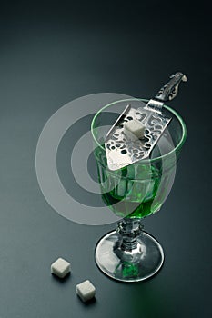 A glass of absinthe and a stainless steel slotted spoon