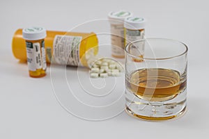 A glass of alcohol and bottles of Pharmaceuticals