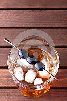 Glass of alcohol drink with olives on pick