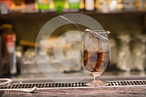 A glass with alcoholic cocktail standing on bar counter. Mixing alcohol drink process. Modern trends in club and bar industry.l