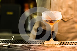 A glass with alcoholic cocktail standing on bar counter. Mixing alcohol drink process. Modern trends in club and bar industry.l