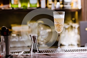 A glass with alcoholic cocktail standing on bar counter. Mixing alcohol drink process. Modern trends in club and bar industry.l