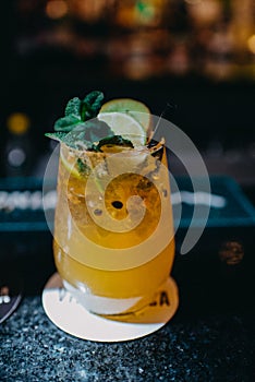 A glass of alcoholic drink with citrics and herbs in a bar