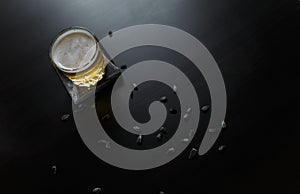 A glass of alcoholic or non-alcoholic beer standing on black wooden table with sunflower seeds around