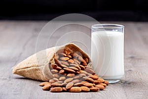 Glass of Almond milk in a glass with Almond seeds. an wooden background