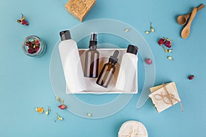 Glass and amber empty bottles. Beauty and cosmetic concept on blue table with flowers around