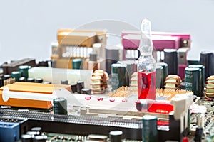 Glass ampoule with red drug with syringe is on socket with cpu processor with contact legs.