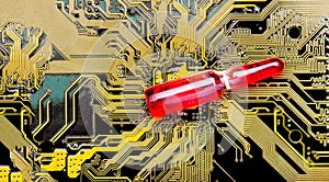 Glass ampoule with a red vaccine on a dark circuit board.