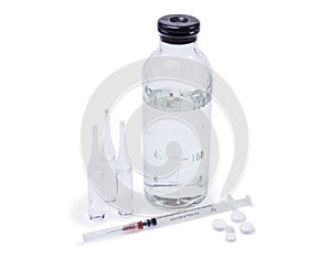 Glass ampoules with medicine, saline bottle, syringe and pills are reflected in a mirror surface isolated on white background