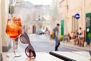 Glass of Aperol Spritz cocktail over Matera streets background