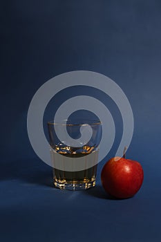 Glass of apple juice and red apple isolated on blue background