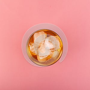 Glass of Apple spritzer or Apfelschorle on pink background, top view. Homemade spritzer with ice cubes. Cold apple juice