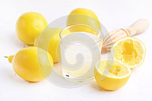 Glass ar of Cold Tasty Fresh Lemonade with Ripe Lemons Wooden Squeezer