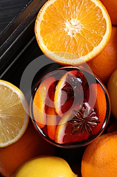 Glass of aromatic punch drink and citrus fruits on table, flat lay