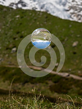 Glass ball floating over pasture in the alps