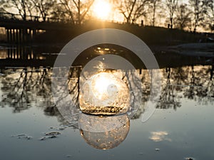 Glass ball on the hand, against the backdrop of a beautiful sunset. Sunset water. Reflection in water