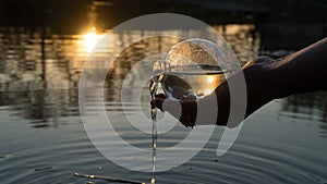 Glass ball on the hand, against the backdrop of a beautiful sunset. Sunset water. Reflection in water