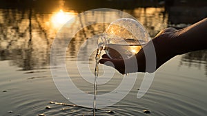 Glass ball on the hand, against the backdrop of a beautiful sunset. Sunset water. Reflection in water