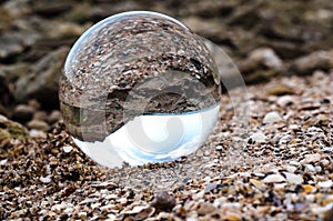 Glass ball lens lies on the sand of the sea shore