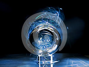 Glass ball on a metal surface and light blue color light painting in the background. Abstract art with reflection and bald rich