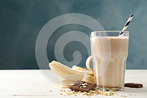 Glass banana - chocolate milkshake on white wooden table