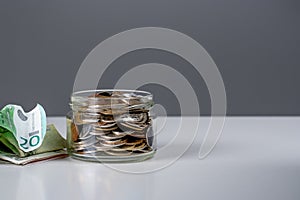 Glass bank for tips with money. Savings concept: coins in jar with copy space for text on dark gray background. Saving money