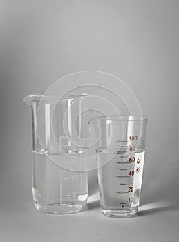 Glass beakers with water on light background