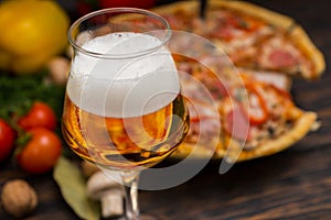 Glass of beer and appetizing pizza with salami on background