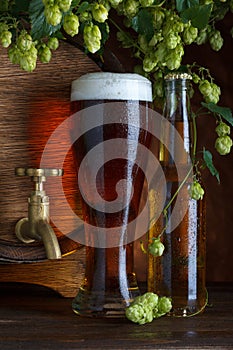 Glass of beer with barrel, bottle and fresh hops