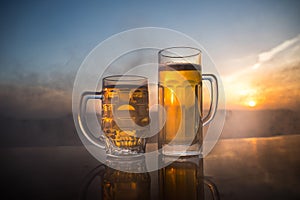 Glass of beer on a beach at sunset. Cooling summer drink concept. Close Up of A Glass of Draught Beer with the Bokeh of Sunlight