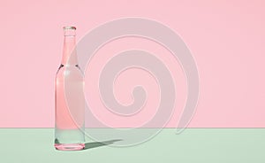 Glass beer bottle on horizontally divided bi-color retro pastel pink and green color background