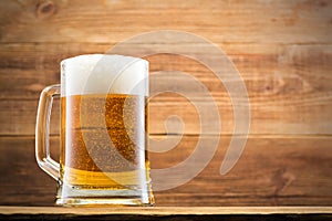 Glass with beer and chips on the background of a wooden wall.