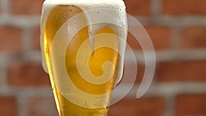 Glass of beer close-up with froth over brick wall