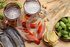 Glass beer with crawfish, hop cones and wheat ears on light wooden background. Beer brewery concept. Beer background. top view