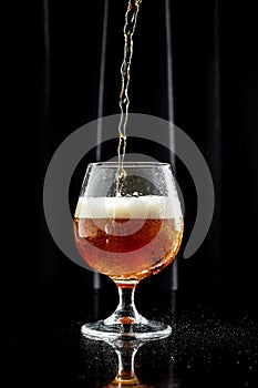 Glass of beer on dark background. beer being poured into glass