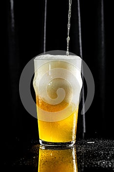 Glass of beer on dark background. beer being poured into glass