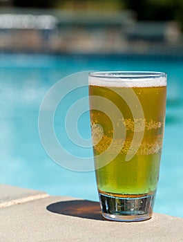 Glass of beer on edge by poolside