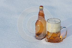 Glass beer with foam, plastic bottle in the snow