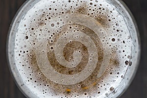 Glass of beer foam on wooden table, top view, close up, macro