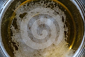 Glass of beer foam on wooden table, top view, close up, macro