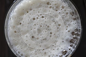 Glass of beer foam on wooden table, top view, close up, macro