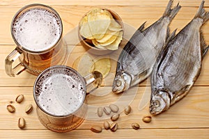 Glass beer with hop cones, dried fish and wheat ears on light wooden background. Beer brewery concept. Beer background. top